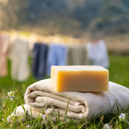Jabón de marsella en un prado, con ropa tendida de fondo
